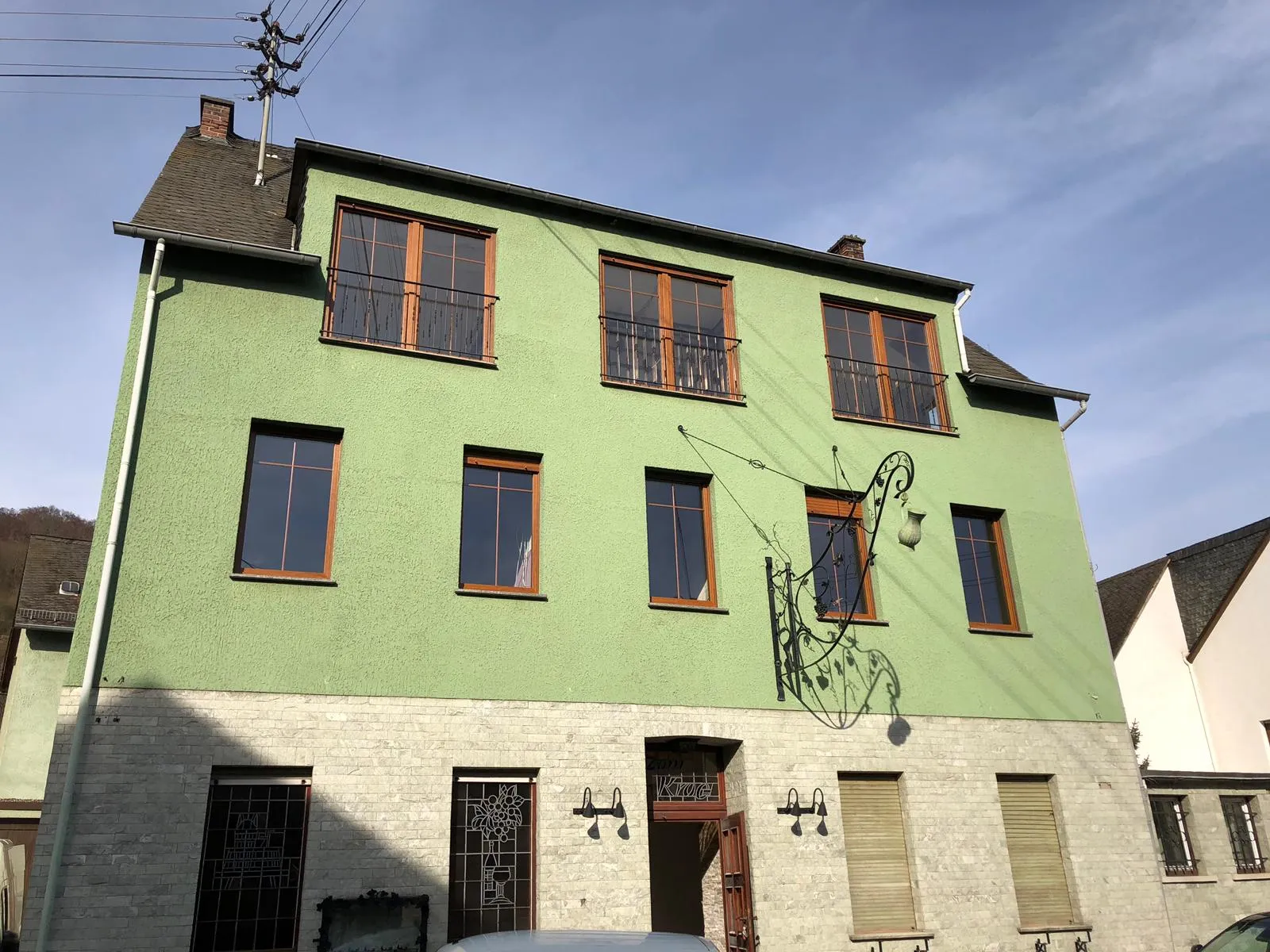 Altbaufassade mit neu eingesetzten Fenstern hinter grün gestrichener Fassade