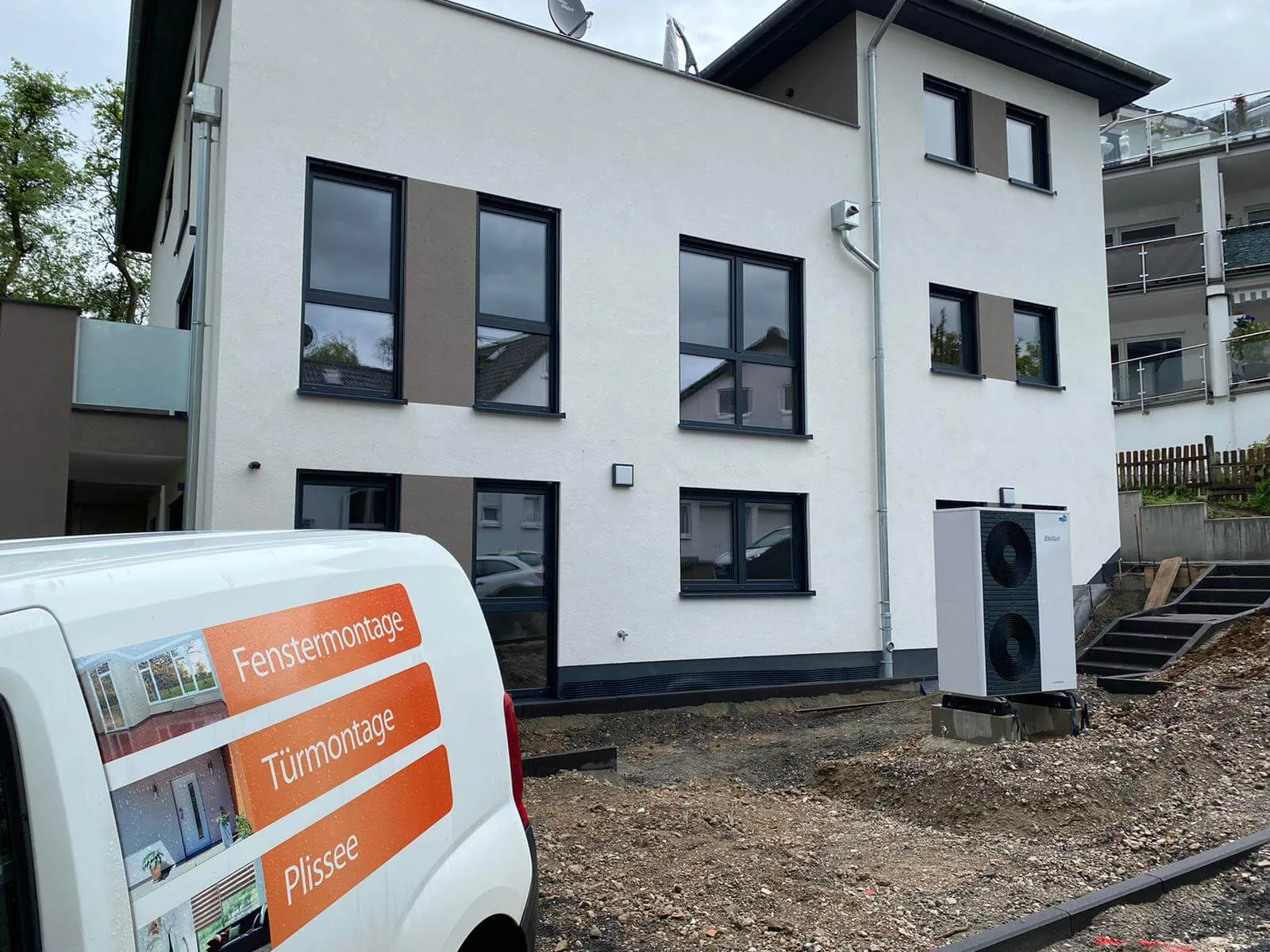 Firmenfahrzeug von Vogel Handwerk vor einem fertiggestellten Neubau mit anthrazitfarbenen Fenstern