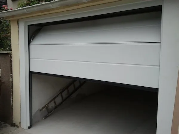 Weißes Schwingtor an einer Bestandsgarage, halb geöffnet