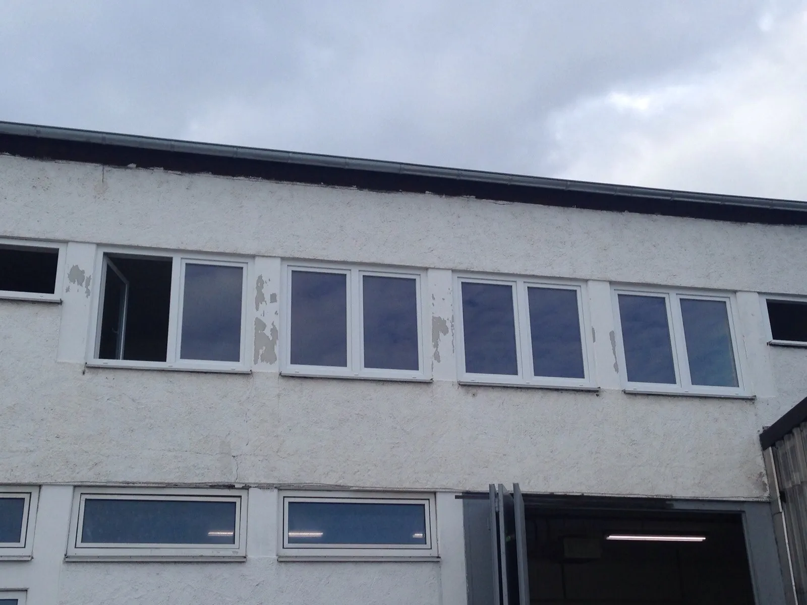 Älteres Gewerbegebäude mit verwitterter Fassade vor dem Fenstertausch