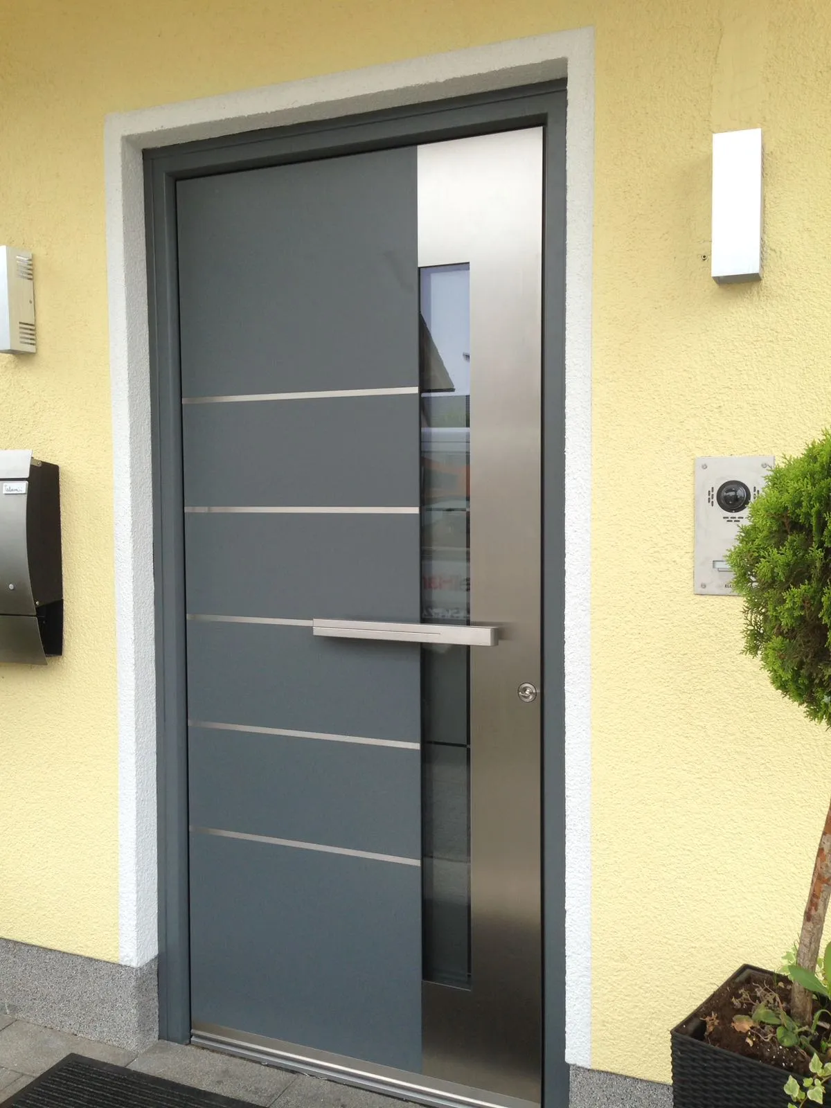 Moderne anthrazitfarbene Haustür mit Edelstahl-Lisenen und schmalem Glasstreifen
