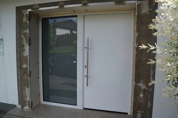 Weiße Haustür mit großem Glas-Seitenteil, Laibung noch unverputzt