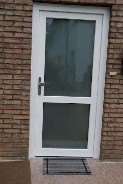 Weiße Nebeneingangstür mit Glasausschnitt in einer Klinkerfassade