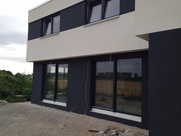 Fertige Putzfassade eines Neubaus mit dunklen Fenstern