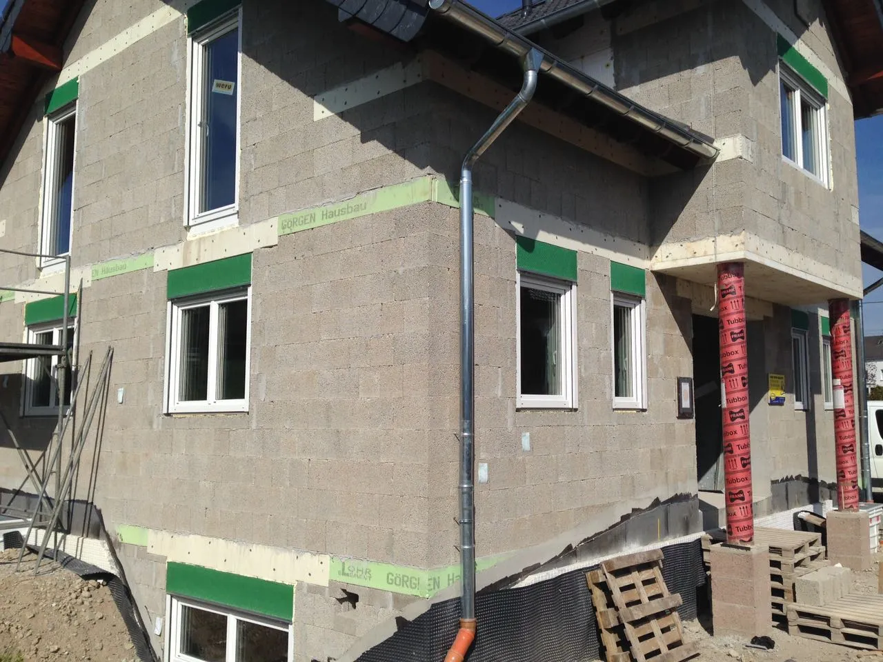 Rohbau mit grauem Mauerwerk und fertig eingesetzten weißen Fenstern